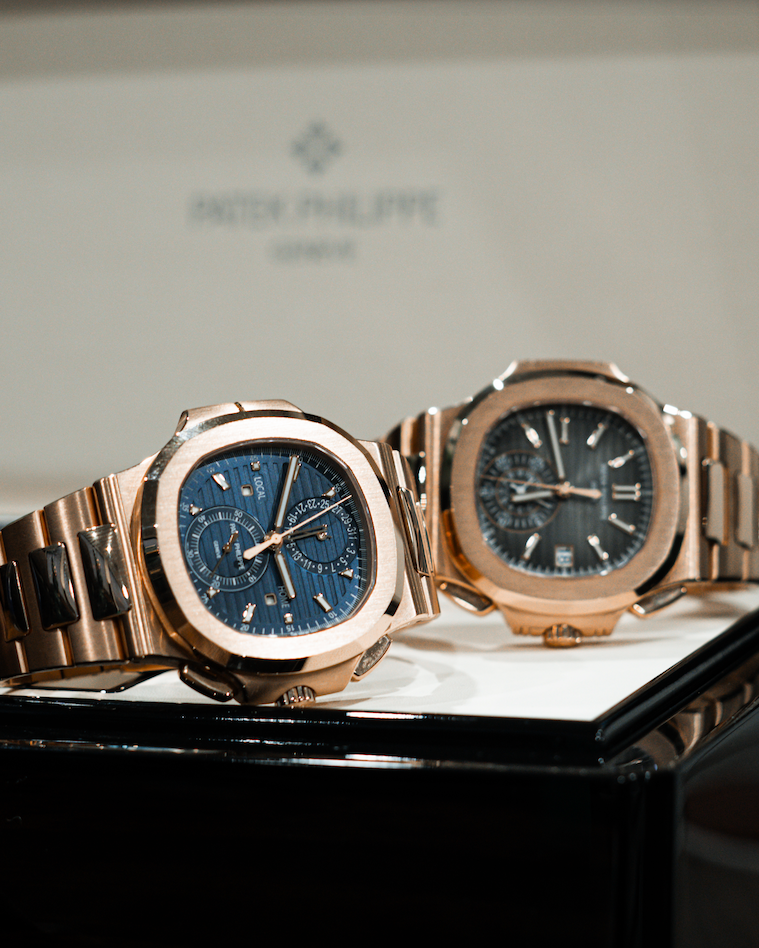 Two rose gold watches on a display stand with a blurred background
