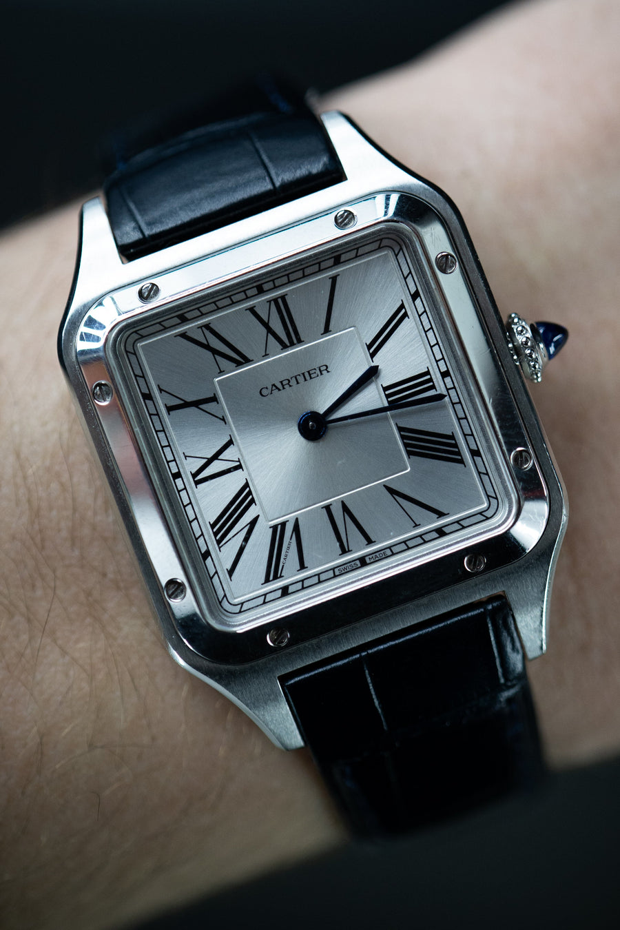 Cartier Dumont Luxury watch with black strap on a wrist against a dark background